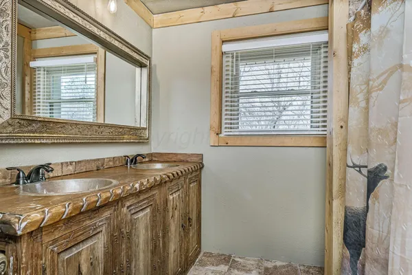 a bathroom with a granite countertop sink and a window