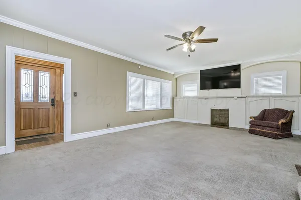 a view of a livingroom with a flat screen tv ceiling fan and windows