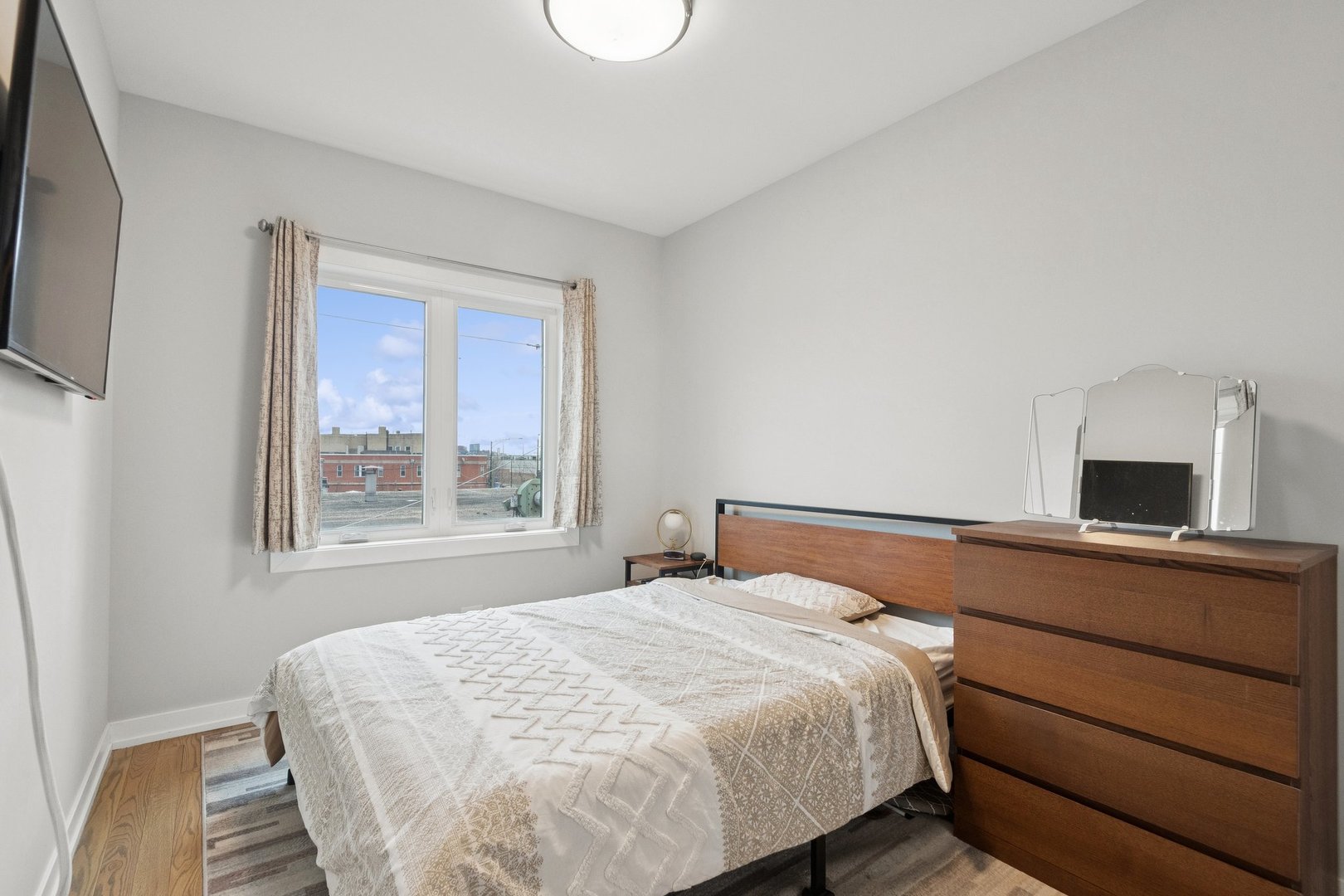 2237 West Coulter Street, Unit 4 Chicago, IL 60608 - Photo 15 of 26 a bedroom with a bed and a flat tv screen on a dresser