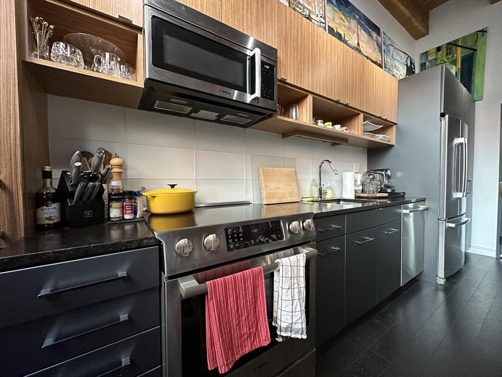319 A Street, Unit 305 Boston, MA 02210 - Photo 5 of 11 a kitchen with stainless steel appliances granite countertop a stove and a microwave
