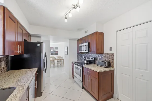 a kitchen with stainless steel appliances granite countertop a stove top oven a refrigerator a sink and dishwasher