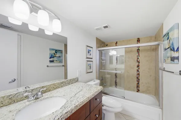 a bathroom with a granite countertop sink a toilet a mirror a vanity and shower