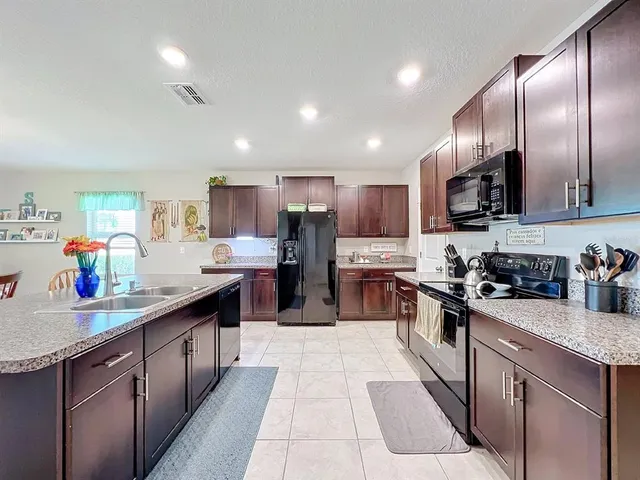 a kitchen with stainless steel appliances kitchen island granite countertop a sink and a refrigerator