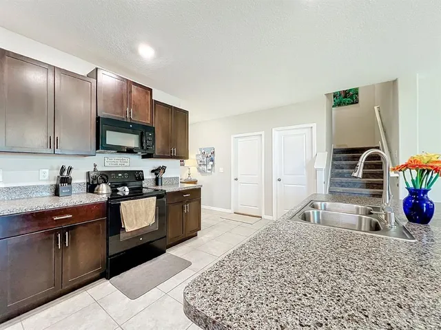a kitchen with stainless steel appliances kitchen island granite countertop a sink refrigerator and cabinets