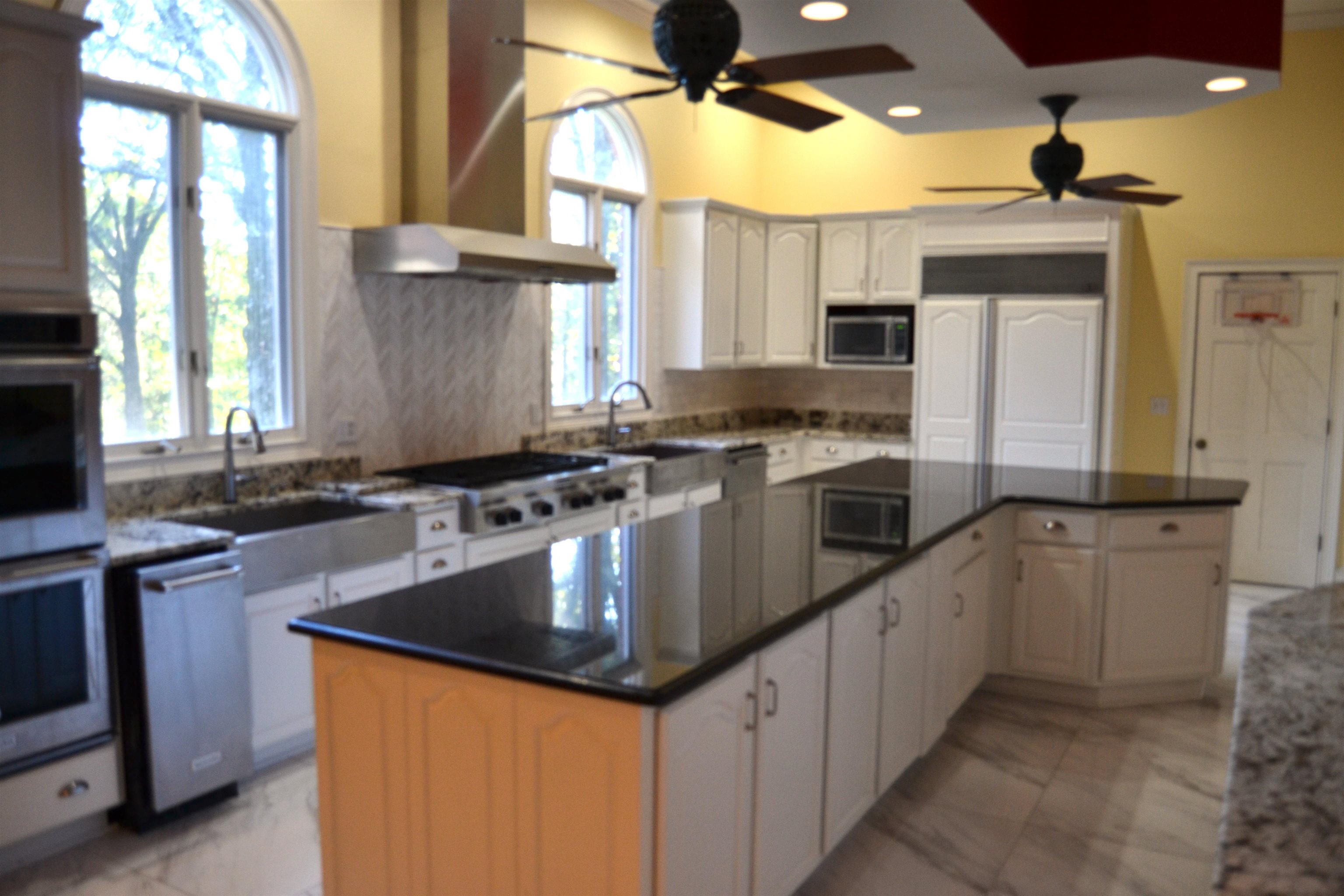470 Walnut Point Cove Memphis, TN 38018 - Photo 19 of 37 Kitchen featuring wall chimney range hood, ceiling fan, stainless steel appliances, a center island, and white cabinets
