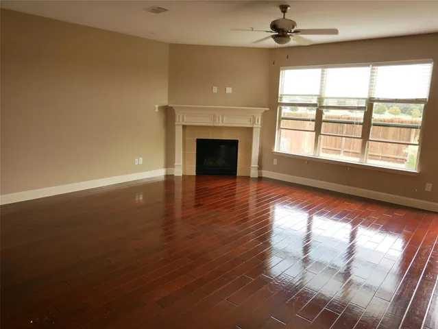 an empty room with wooden floor fireplace and windows