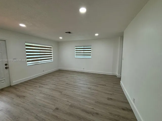 an empty room with wooden floor and entrance