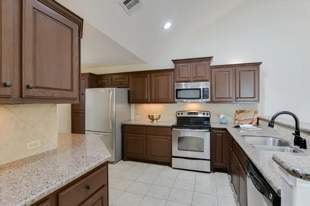 a kitchen with stainless steel appliances granite countertop a refrigerator stove and sink