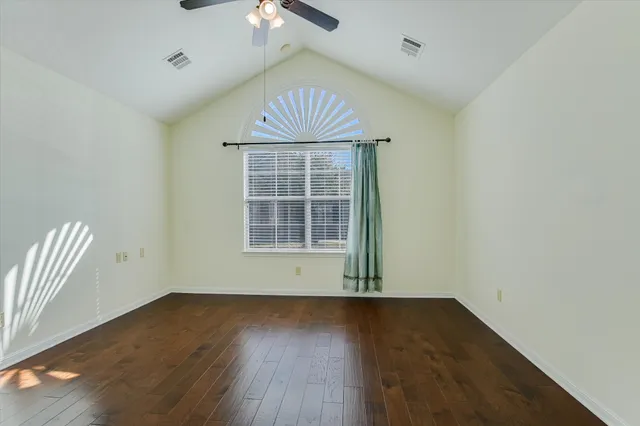 an empty room with wooden floor fan and windows