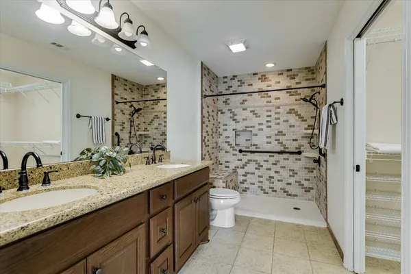 a bathroom with a granite countertop sink a toilet a mirror a shower and vanity