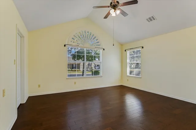 a view of an empty room with a window and wooden floor