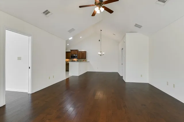 a view of empty room with wooden floor and ceiling fan