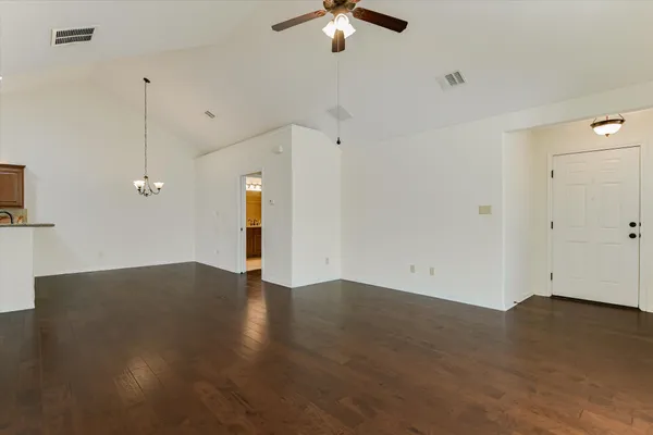 an empty room with wooden floor ceiling fan and window