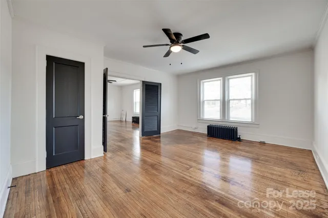 a view of empty room with wooden floor and window