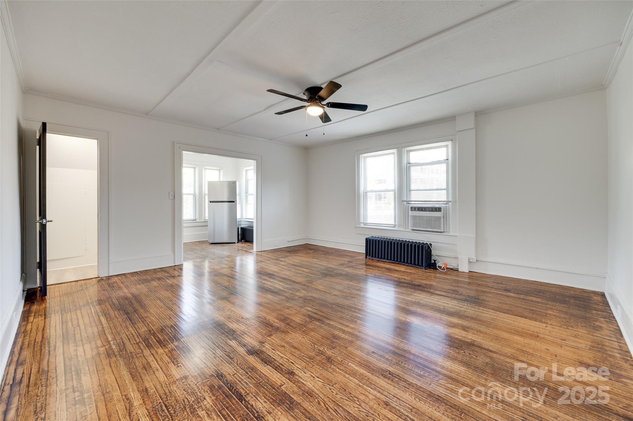49 Corban Avenue Southwest, Unit 3 Concord, NC 28025 - Photo 5 of 16 an empty room with wooden floor ceiling fan and windows