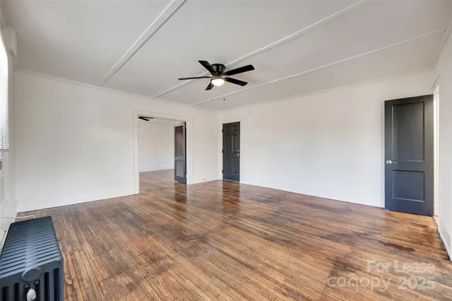 a view of an empty room with a window and wooden floor