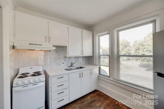 a kitchen with a stove a sink and a window