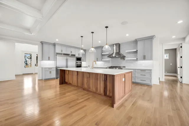 a large kitchen with stainless steel appliances sink a large counter top and wooden floors