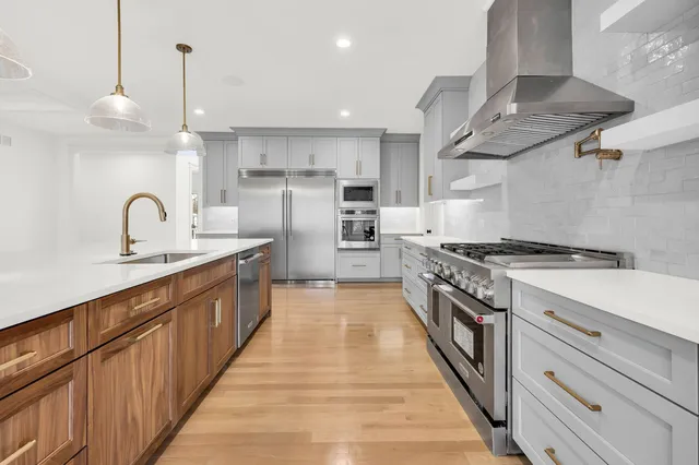 a large kitchen with stainless steel appliances granite countertop a large counter top a stove and a refrigerator