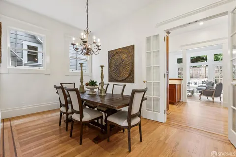 a living room with furniture a chandelier and wooden floor
