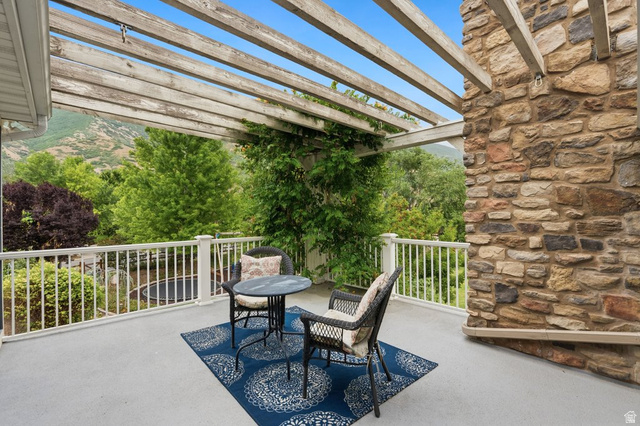 672 Perry Hollow Drive Mapleton, UT 84664 - Photo 47 of 106 Expansive outdoor deck featuring a wooden pergola, stone wall accent, white railing, and surrounding mature trees