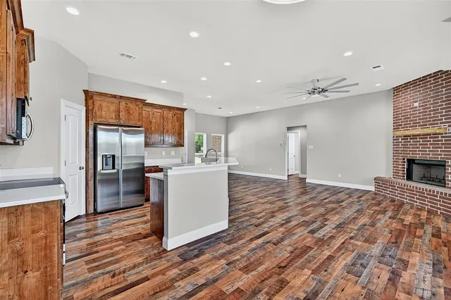 a kitchen with stainless steel appliances kitchen island granite countertop a refrigerator a sink a stove and oven