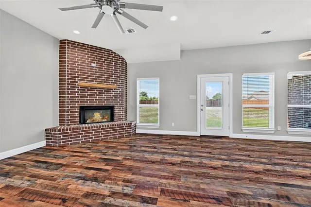 a view of an empty room with a fireplace and windows