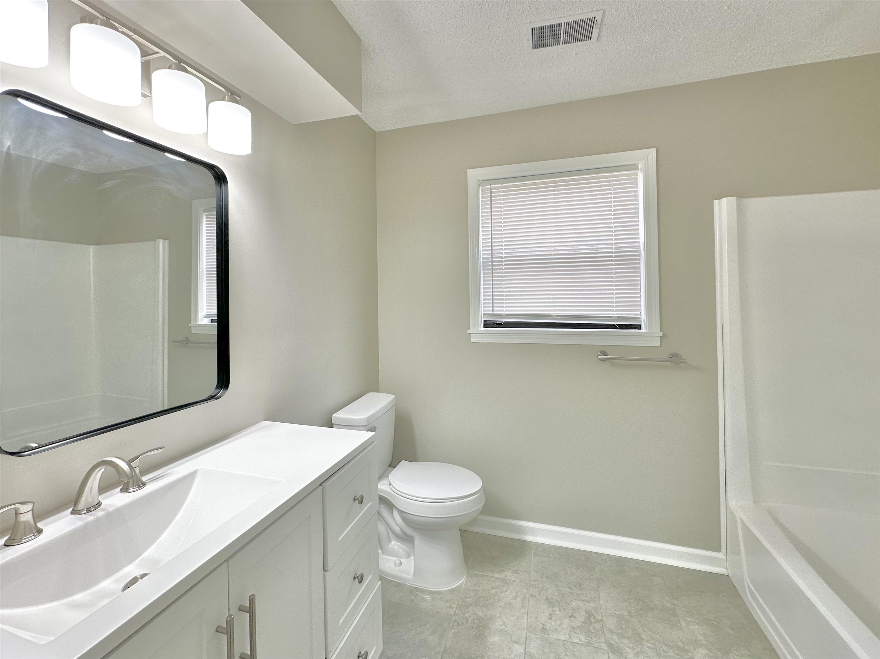 4376 Coleman Road Memphis, TN 38128 - Photo 18 of 21 a bathroom with a granite countertop toilet a sink a mirror and a window