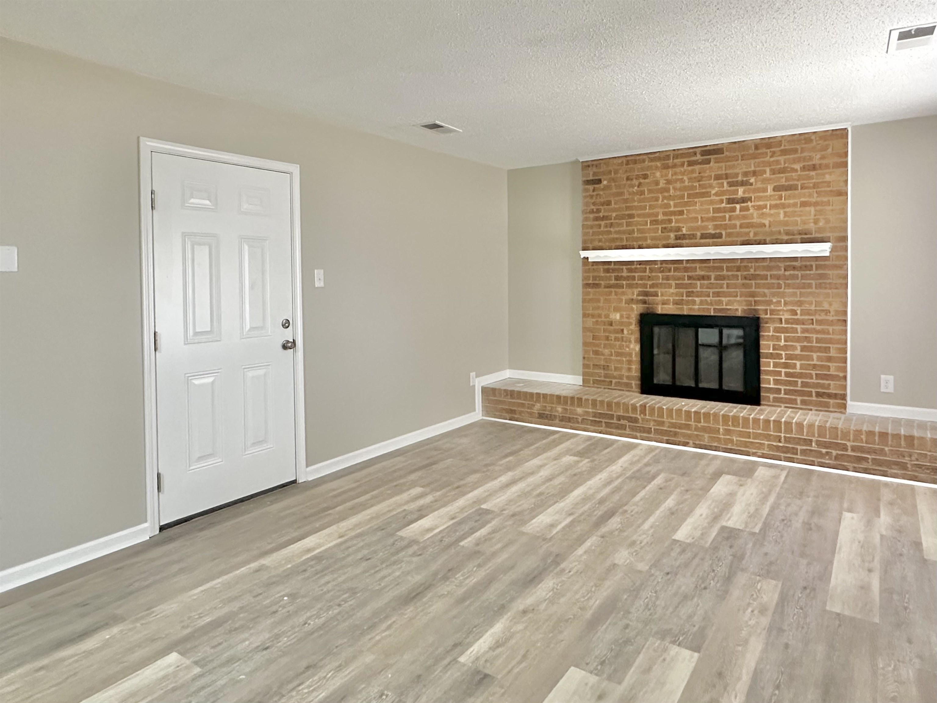 4376 Coleman Road Memphis, TN 38128 - Photo 3 of 21 an empty room with wooden floor fireplace and windows