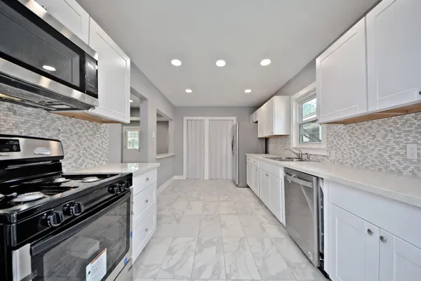 a large kitchen with stainless steel appliances granite countertop a stove and a sink