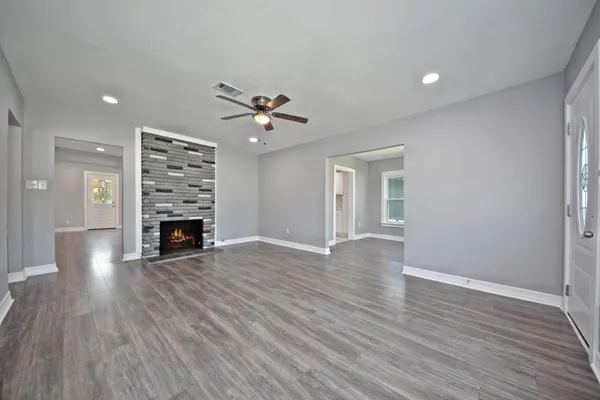 a view of an empty room with a window and wooden floor