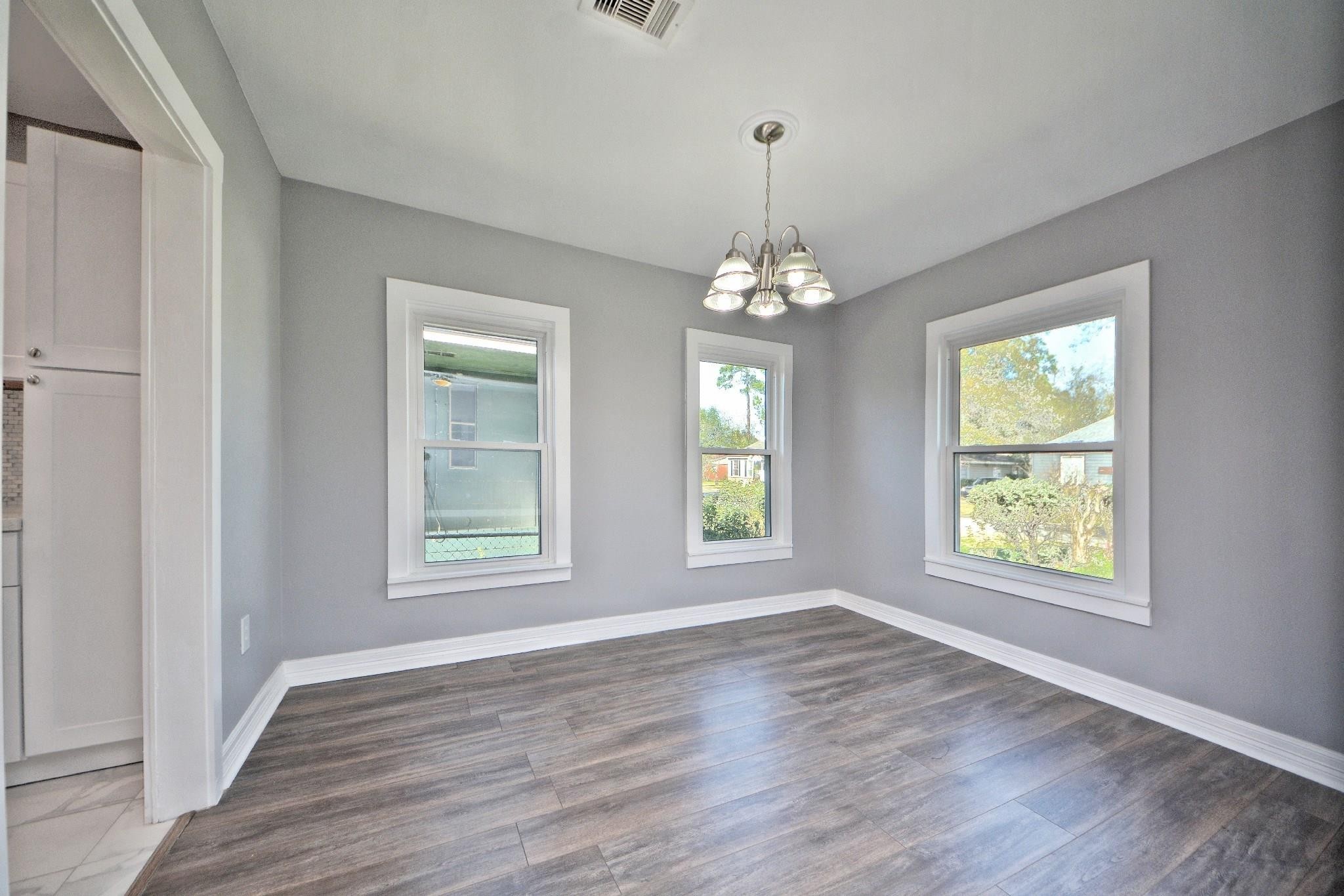 3834 Rosedale Street Houston, TX 77004 - Photo 23 of 48 an empty room with wooden floor chandelier and windows
