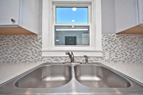a kitchen with granite countertop a refrigerator and white cabinets