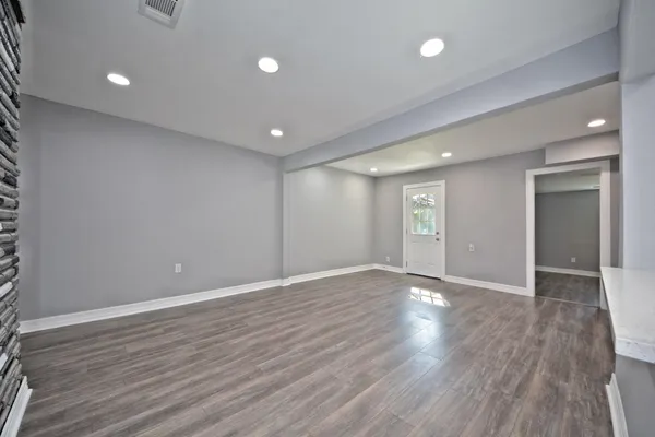 a view of an empty room with wooden floor and a window