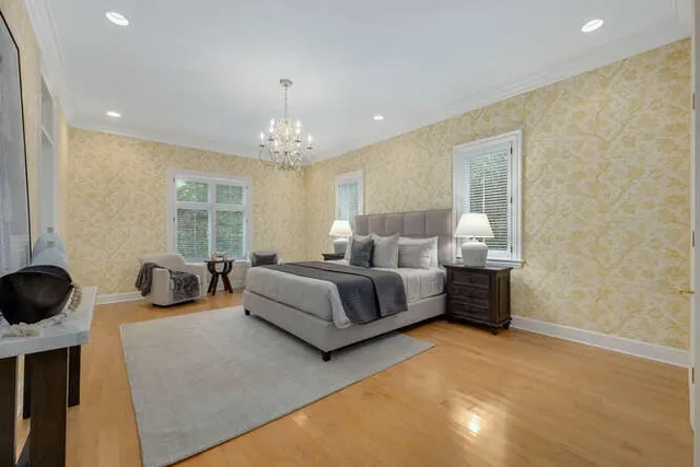 a bedroom with a bed couch chandelier and a window