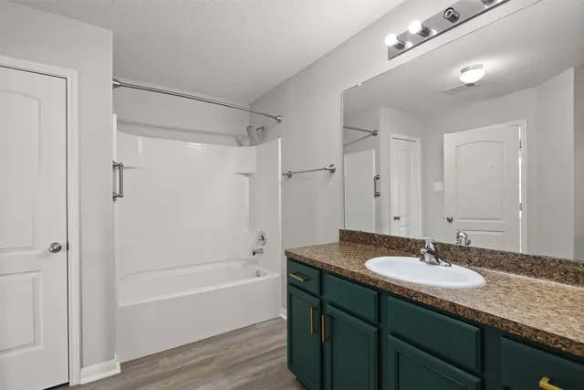 a bathroom with a granite countertop sink a mirror a bathtub and shower