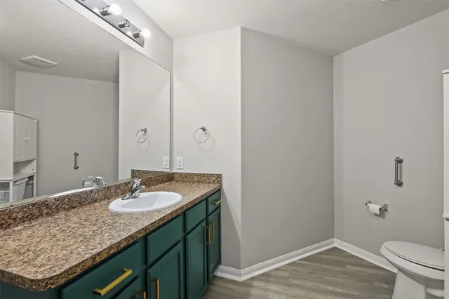 a bathroom with a granite countertop sink a toilet and shower