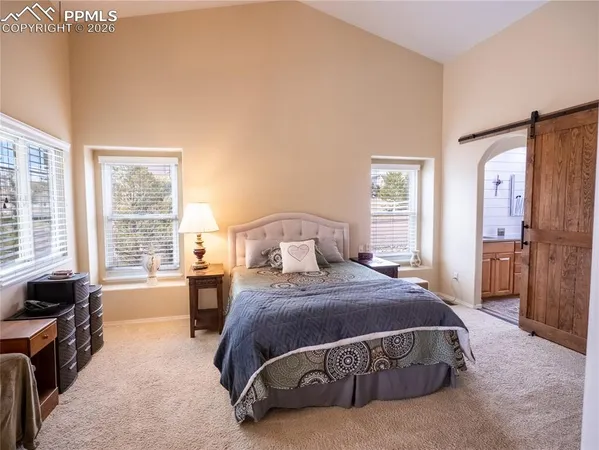 a spacious bedroom with a bed a table and windows