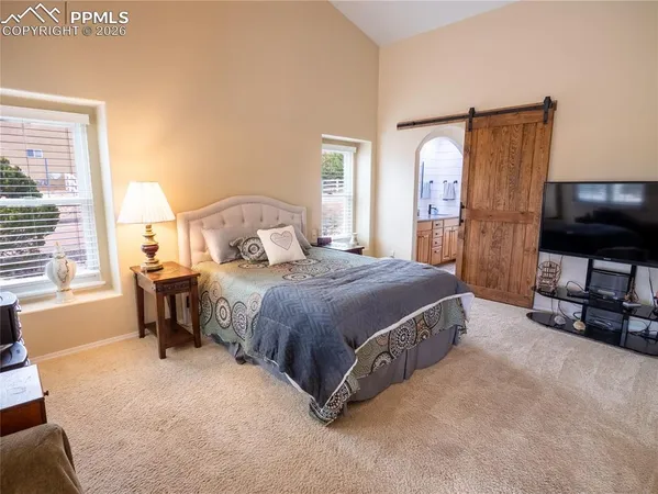 a bedroom with a bed flat screen tv and a large window
