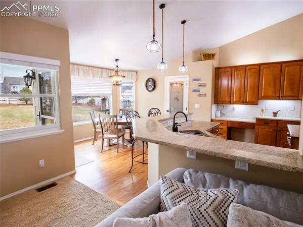 a kitchen with stainless steel appliances kitchen island granite countertop a stove a sink a dining table and chairs with wooden floor