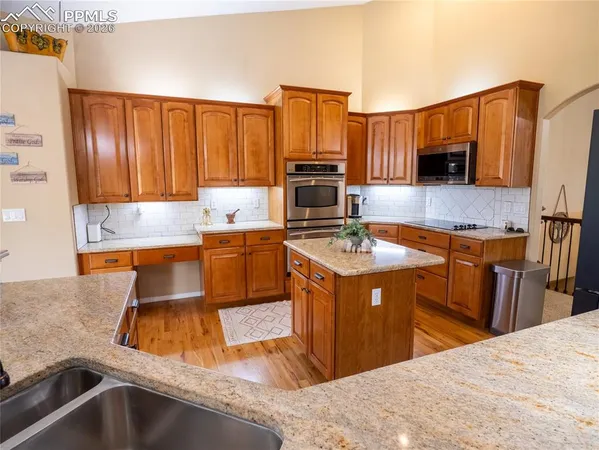 a kitchen with kitchen island granite countertop a sink a counter top space appliances and cabinets