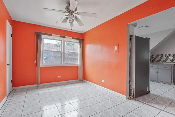 an empty room with chandelier fan and windows