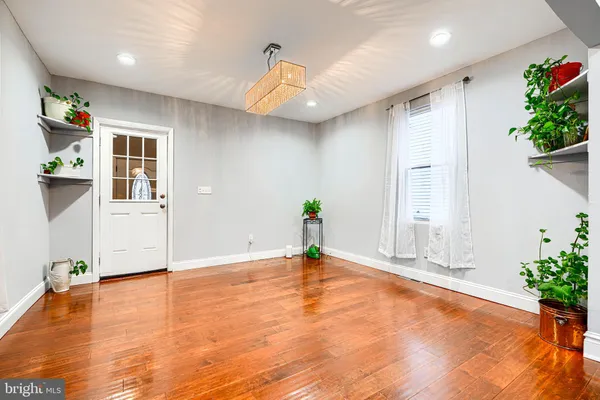 a view of an empty room with wooden floor and a potted plant