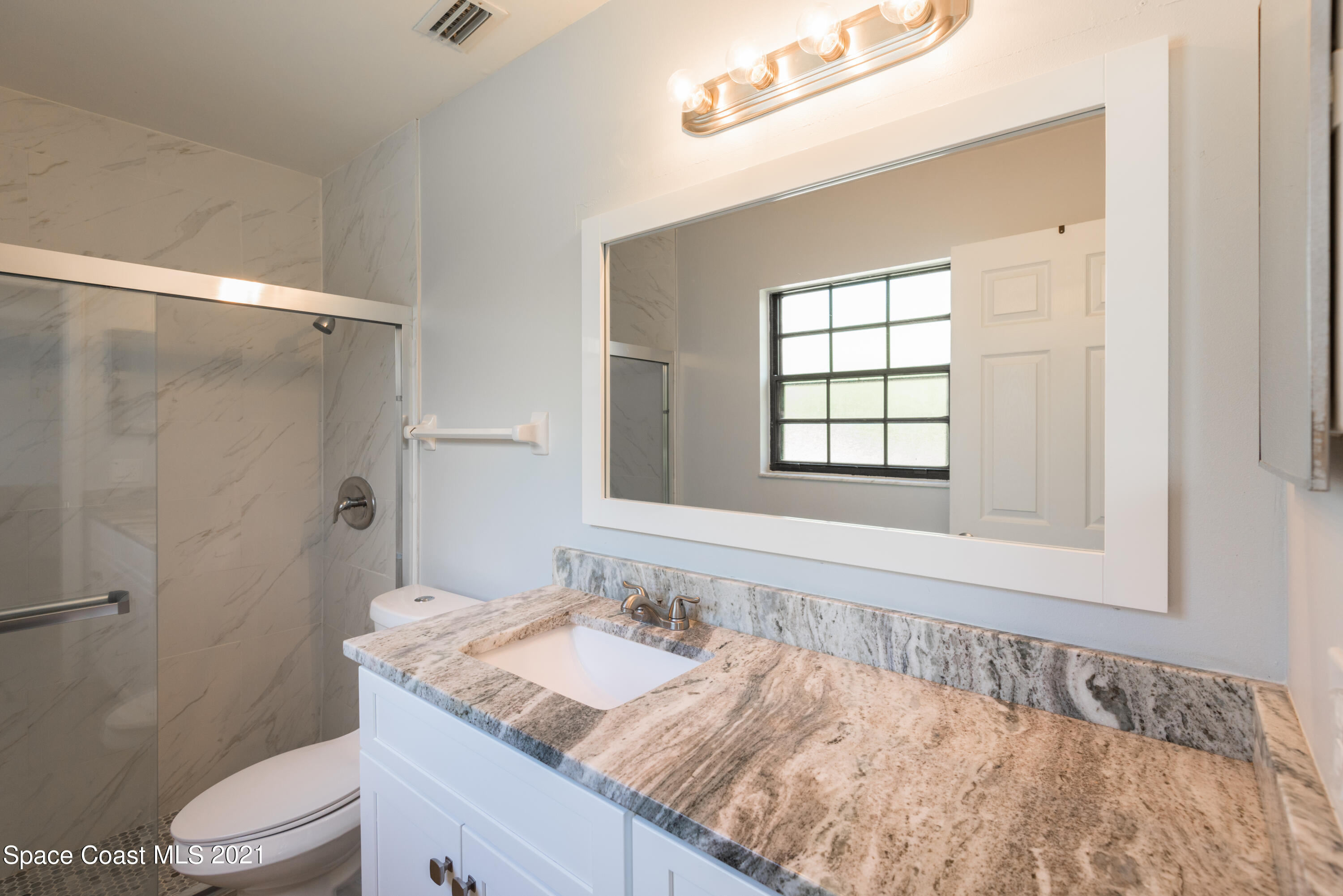 1077 San Rafael Road Southwest Palm Bay, FL 32908 - Photo 7 of 13 a bathroom with a granite countertop sink a toilet and shower
