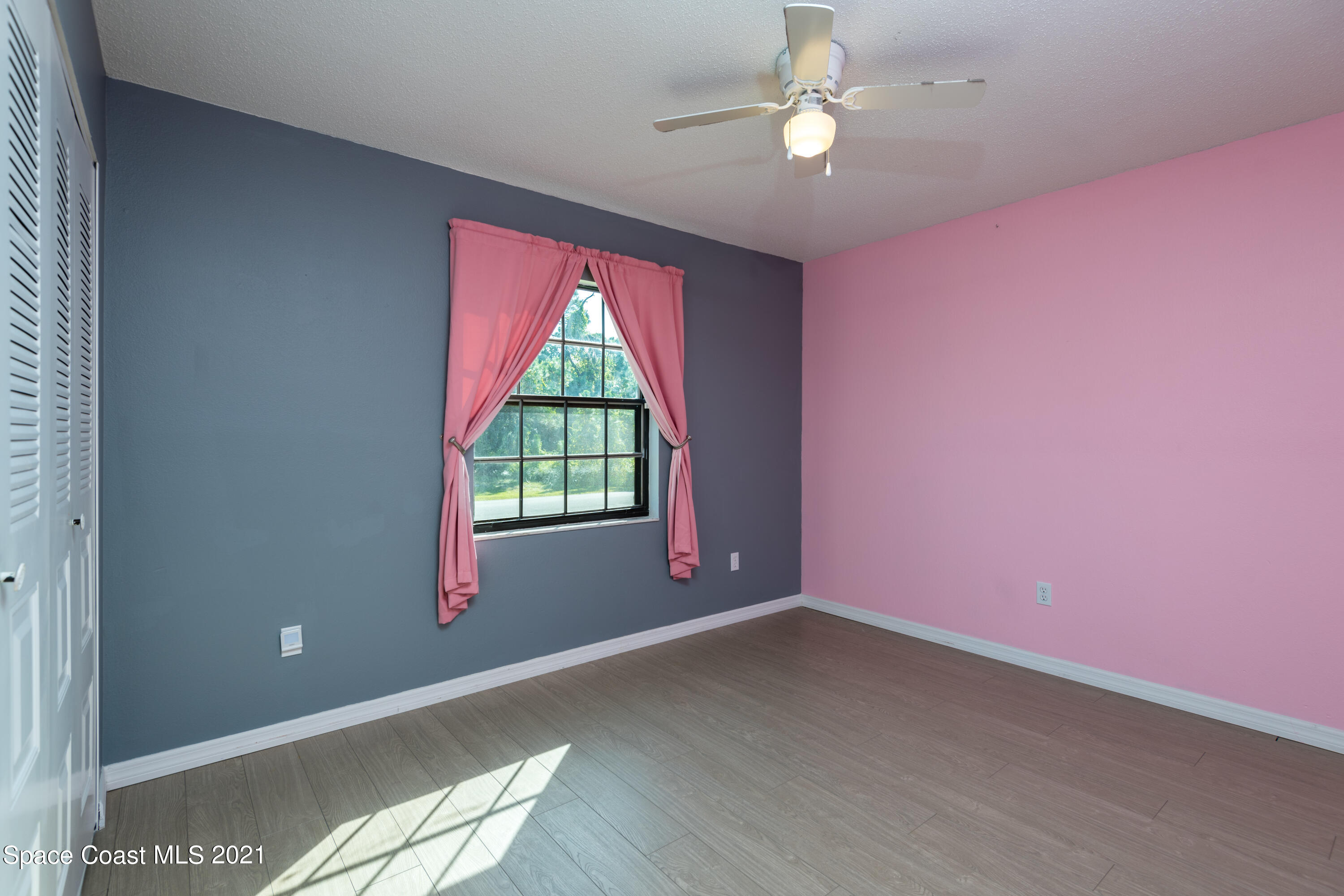1077 San Rafael Road Southwest Palm Bay, FL 32908 - Photo 9 of 13 an empty room with chandelier fan and windows