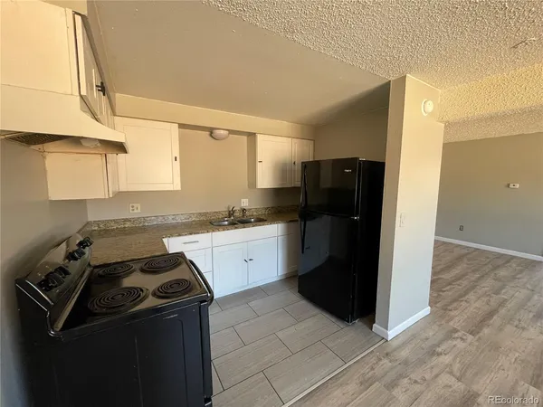 a kitchen with granite countertop a refrigerator and a stove top oven