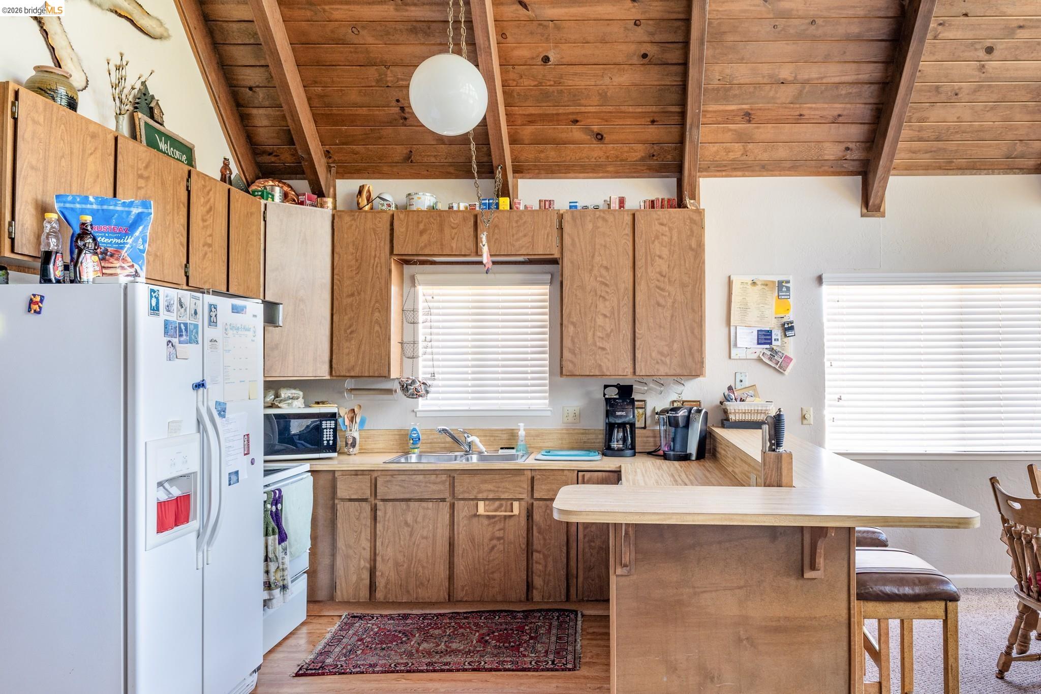 19711 Pleasantview Drive Groveland, CA 95321 - Photo 17 of 39 Kitchen featuring wood-finish cabinetry, light-colored countertops, and a wood-paneled vaulted ceiling with exposed beams