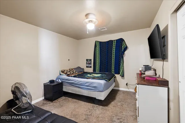 a bedroom with bed and a flat tv screen on dresser