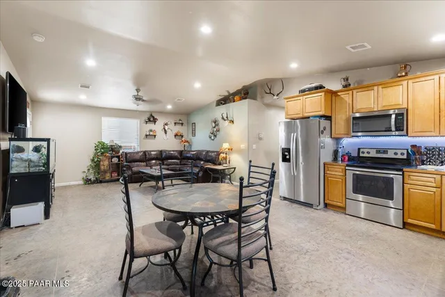 a kitchen with stainless steel appliances kitchen island granite countertop a table chairs and a refrigerator