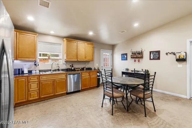 a kitchen with stainless steel appliances granite countertop a sink a stove a dining table and chairs